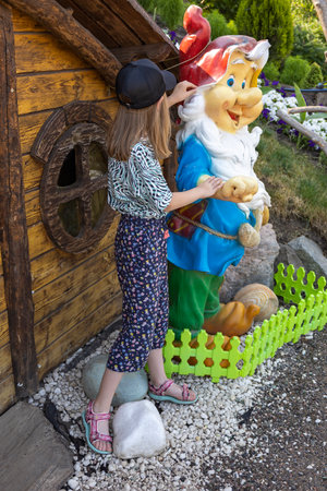 A little girl near a figure of a garden gnome.の写真素材