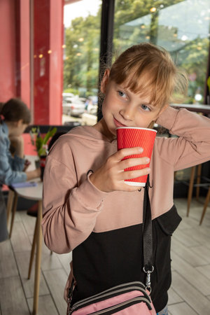 A little girl drinks coffee from a paper cup.の写真素材