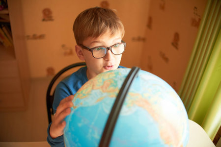 Boy with a globe. The boy in the glasses sees the globeの写真素材