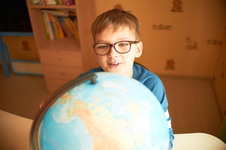 Boy with a globe. The boy in the glasses sees the globeの写真素材
