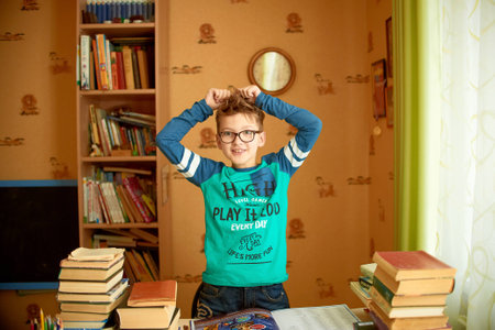 education, childhood, people, homework and school concept - bored student boy reading book or textbook at homeの写真素材