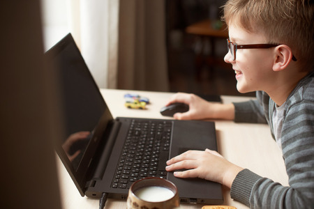 Happy boy sitting at his desk With laptop computerの写真素材