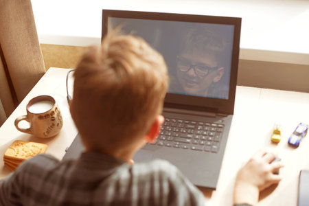 Happy boy sitting at his desk With laptop computer