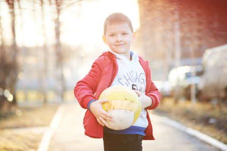 boy in a red jacket, pants, sneakers plays soccer, enjoys running, kicking the ball, smilingの写真素材