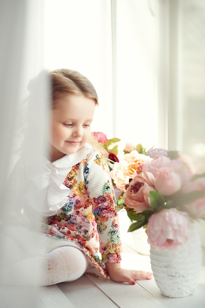 Small girl in colorful dress with flowers in hair. Facial expression.の写真素材