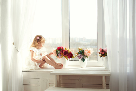 Small girl in colorful dress with flowers in hair. Facial expression.の写真素材