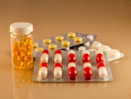 Blisters with red-white capsules and a jar of drugs. Blister with yellow pills blurred in the backgroundの写真素材