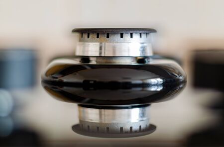 Gas burner without flame on the stove with a glass surface and reflection. Frontal shot with a...