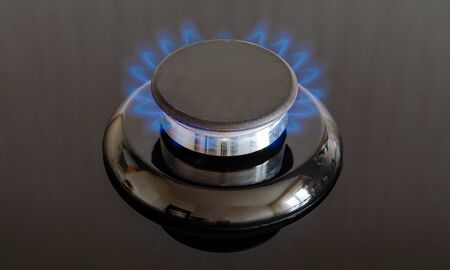 Gas burner with a flame on the stove with a glass surface. Frontal close-up shot, full frameの写真素材