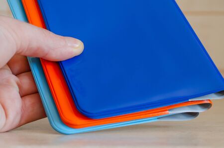 Multicolored shiny passport covers in hand, closeup shot