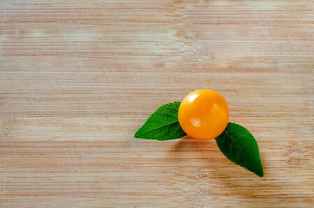 Cherry plum with green leaves on a wooden surface. Wood texture. Empty space. Close-upの写真素材
