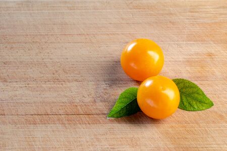 Two cherry plums with green leaves on a wooden surface. Wood texture. Empty space. Close-upの写真素材