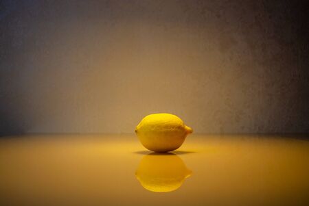 Yellow lemon with reflection with a halo of yellow lighting. Fruit with reflection on a glass...