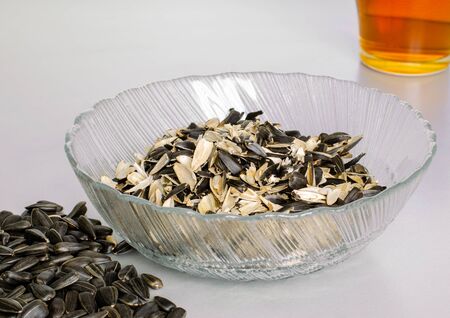 A transparent plate with husks from sunflower seeds. And a scattering of seeds and a cup of tea. Top view at an angleの写真素材