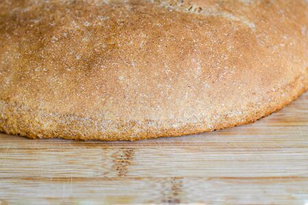 Semicircle of whole grain bread on a light wooden surface. Bakery, food concept. Country style. Close upの写真素材