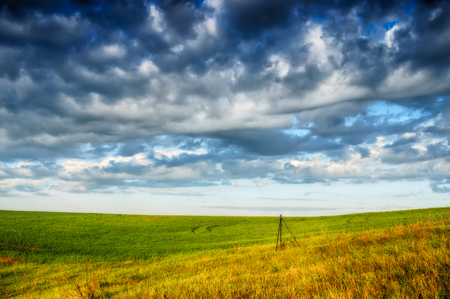 a hilly field. gloomy clouds over the fieldの写真素材