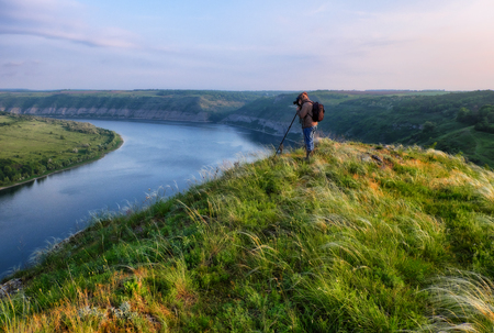 photographer on the cliff above the river. the tourist watches the sunset over the canyonの写真素材