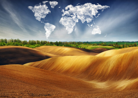 clouds in the form of a map of the world over the field. Travel and landscape concept. hilly field