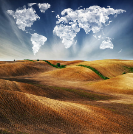 clouds in the form of a map of the world over the field. Travel and landscape concept. hilly fieldの写真素材