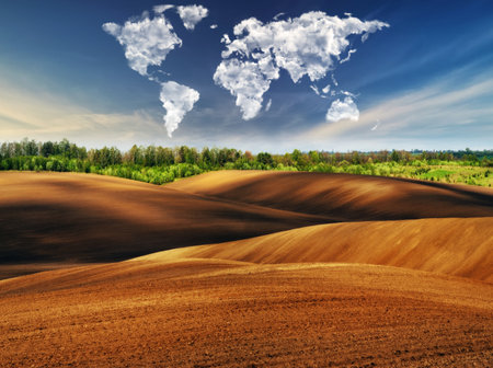 clouds in the form of a map of the world over the field. Travel and landscape concept. hilly fieldの写真素材