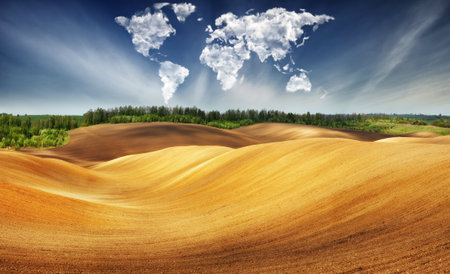 clouds in the form of a map of the world over the field. Travel and landscape concept. hilly fieldの写真素材