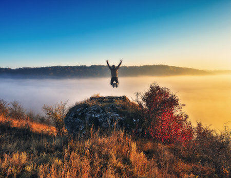 Autumn morning. Traveler on the top of rocks above river valley with thick fog. Natureの写真素材