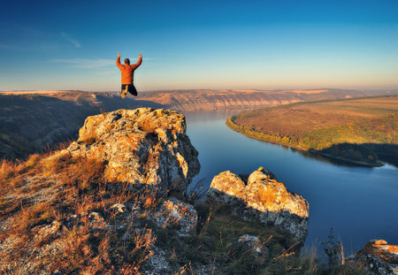 Autumn morning. Traveler on the top of rocks above river valley with thick fog. Natureの写真素材