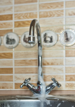 Close-up of a filthy kitchen tap covered in cleaning foamの写真素材