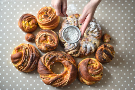 Close-up of a woman's hand using a sieve to dust sweet Easter bread (Paska) with white powdered sugarの写真素材