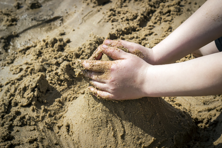 Child's hand build stronghold in salt white sand and.の写真素材