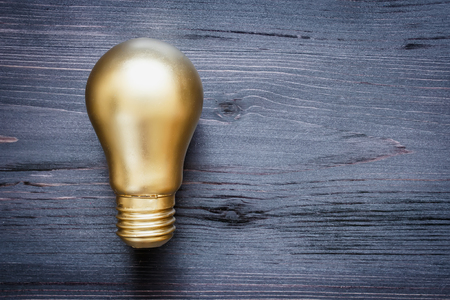 Gold bulb on a black wooden backgroundの写真素材