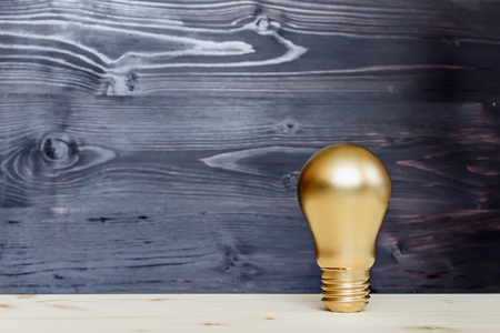 Gold bulb on a black wooden backgroundの写真素材