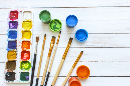 Paints and brushes on a white wooden backgroundの写真素材