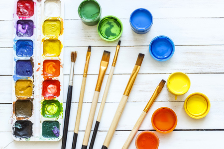 Paints and brushes on a white wooden backgroundの写真素材