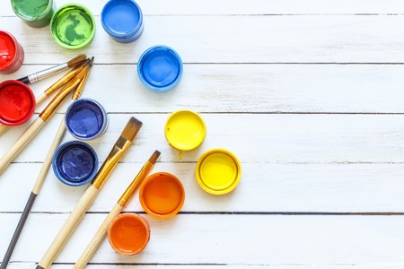 Paints and brushes on a white wooden backgroundの写真素材