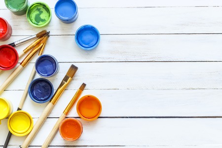Paints and brushes on a white wooden backgroundの写真素材