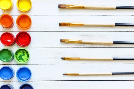 Paints and brushes on a white wooden backgroundの写真素材