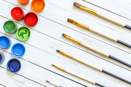 Paints and brushes on a white wooden backgroundの写真素材