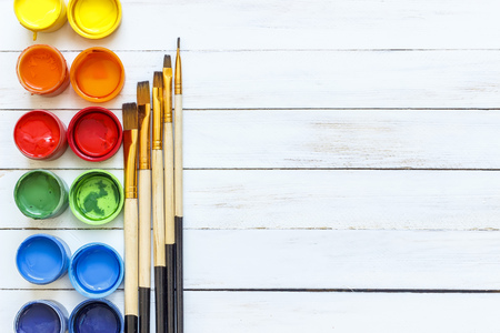 Paints and brushes on a white wooden backgroundの写真素材
