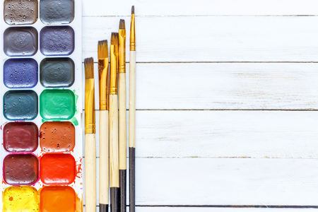 Paints and brushes on a white wooden backgroundの写真素材