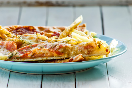 Pizza, French fries on the plate on white wooden backgroundの写真素材