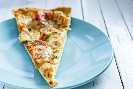 Pizza on a blue plate on a white wooden backgroundの写真素材