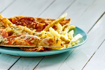 Pizza, French fries on the plate on white wooden backgroundの写真素材