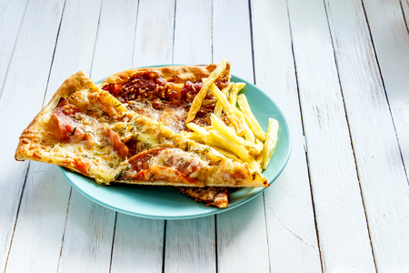 Pizza, French fries on the plate on white wooden backgroundの写真素材