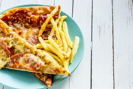 Pizza, French fries on the plate on white wooden backgroundの写真素材