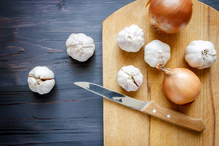 Onion, garlic and knife on a black wooden backgroundの写真素材