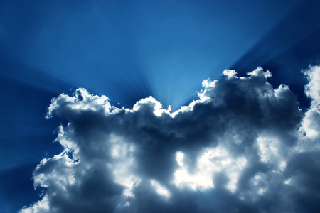 Light ray from sun behind cloud in the blue skyの写真素材
