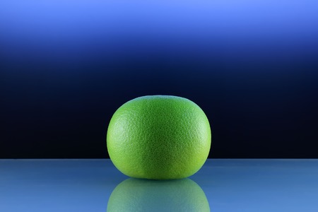 Grapefruit isolated photo Whole ripe citrus sweetie is lying on a blue background Close-up fruit photo. minimal creative still lifeの写真素材