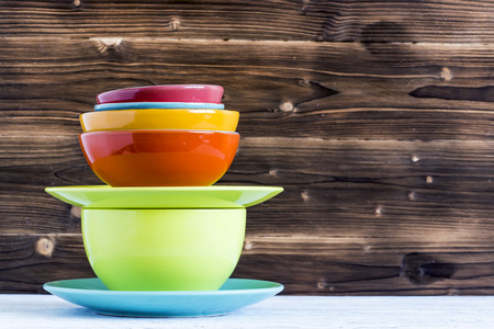Empty color plates and utensil on wooden table background, with copy spaceの写真素材
