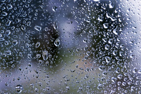 Rain drops on window glasses surface with cloudy background .